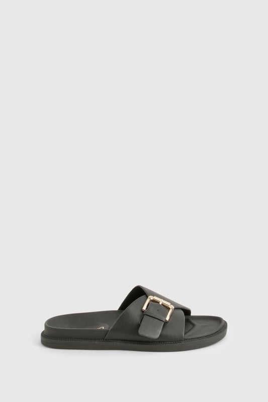 Sleek single-strap design with adjustable metal buckle detail
        Flat sole with comfortable 0-2cm heel height for all-day wear
        Smooth PU construction offering durability and easy maintenance
        Wide foot strap with contemporary minimalist aesthetic
        Slip-on style for effortless wearing and removal
    
    These versatile buckled sandals are the perfect addition to your casual wardrobe. The minimalist design pairs brilliantly with frayed denim as shown, but works equally well with floaty summer dresses or tailored shorts. The adjustable buckle ensures a customised fit while maintaining the clean, unfussy silhouette that makes these sandals so adaptable. Ideal for city breaks where comfort meets style, they'll take you from daytime sightseeing to casual evening meals without missing a beat. The flat profile offers stability for long walks, whilst the simple design ensures they'll complement virtually any outfit in your holiday collection. Perfect for family gatherings, weekend brunches or casual shopping trips when you need footwear that combines practicality with Boohoo's signature contemporary flair.