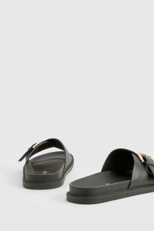 Sleek single-strap design with adjustable metal buckle detail
        Flat sole with comfortable 0-2cm heel height for all-day wear
        Smooth PU construction offering durability and easy maintenance
        Wide foot strap with contemporary minimalist aesthetic
        Slip-on style for effortless wearing and removal
    
    These versatile buckled sandals are the perfect addition to your casual wardrobe. The minimalist design pairs brilliantly with frayed denim as shown, but works equally well with floaty summer dresses or tailored shorts. The adjustable buckle ensures a customised fit while maintaining the clean, unfussy silhouette that makes these sandals so adaptable. Ideal for city breaks where comfort meets style, they'll take you from daytime sightseeing to casual evening meals without missing a beat. The flat profile offers stability for long walks, whilst the simple design ensures they'll complement virtually any outfit in your holiday collection. Perfect for family gatherings, weekend brunches or casual shopping trips when you need footwear that combines practicality with Boohoo's signature contemporary flair.