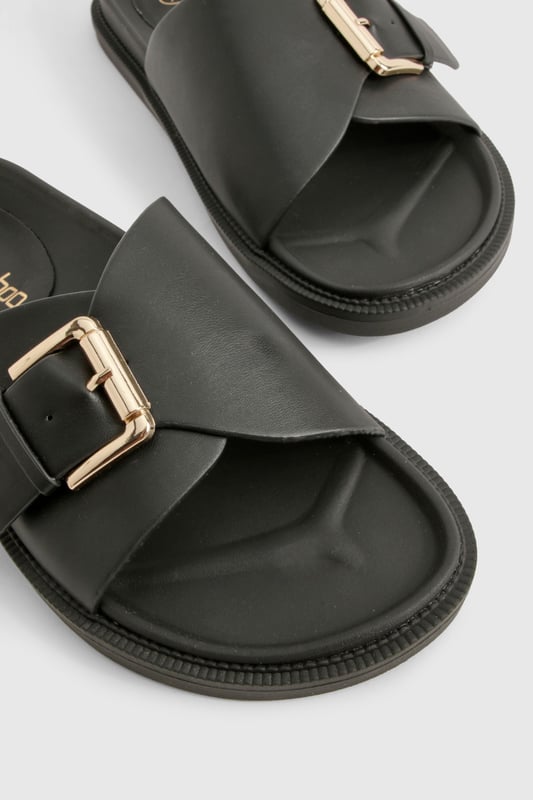 Sleek single-strap design with adjustable metal buckle detail
        Flat sole with comfortable 0-2cm heel height for all-day wear
        Smooth PU construction offering durability and easy maintenance
        Wide foot strap with contemporary minimalist aesthetic
        Slip-on style for effortless wearing and removal
    
    These versatile buckled sandals are the perfect addition to your casual wardrobe. The minimalist design pairs brilliantly with frayed denim as shown, but works equally well with floaty summer dresses or tailored shorts. The adjustable buckle ensures a customised fit while maintaining the clean, unfussy silhouette that makes these sandals so adaptable. Ideal for city breaks where comfort meets style, they'll take you from daytime sightseeing to casual evening meals without missing a beat. The flat profile offers stability for long walks, whilst the simple design ensures they'll complement virtually any outfit in your holiday collection. Perfect for family gatherings, weekend brunches or casual shopping trips when you need footwear that combines practicality with Boohoo's signature contemporary flair.