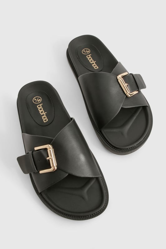 Sleek single-strap design with adjustable metal buckle detail
        Flat sole with comfortable 0-2cm heel height for all-day wear
        Smooth PU construction offering durability and easy maintenance
        Wide foot strap with contemporary minimalist aesthetic
        Slip-on style for effortless wearing and removal
    
    These versatile buckled sandals are the perfect addition to your casual wardrobe. The minimalist design pairs brilliantly with frayed denim as shown, but works equally well with floaty summer dresses or tailored shorts. The adjustable buckle ensures a customised fit while maintaining the clean, unfussy silhouette that makes these sandals so adaptable. Ideal for city breaks where comfort meets style, they'll take you from daytime sightseeing to casual evening meals without missing a beat. The flat profile offers stability for long walks, whilst the simple design ensures they'll complement virtually any outfit in your holiday collection. Perfect for family gatherings, weekend brunches or casual shopping trips when you need footwear that combines practicality with Boohoo's signature contemporary flair.