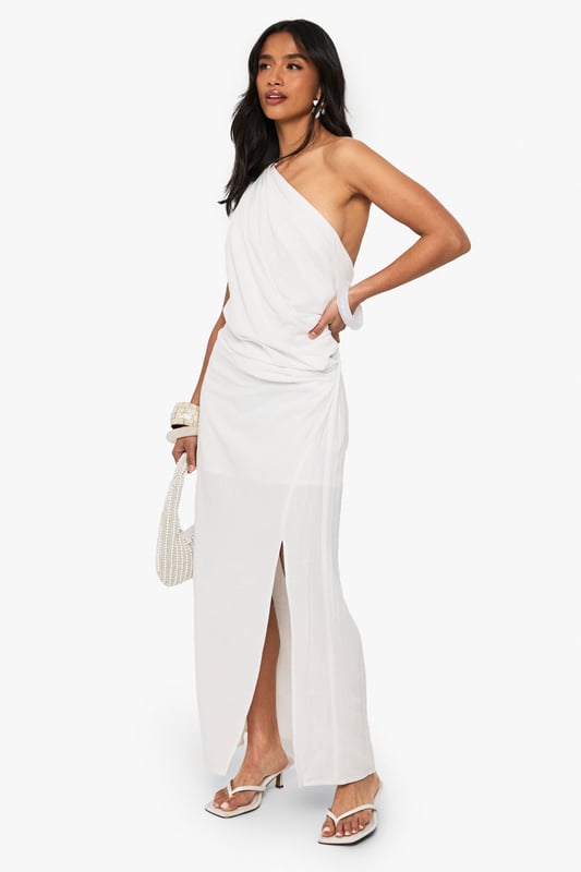 Striking one-shoulder design with elegant draping detail
        Flowing maxi length with side split for effortless movement
        Dramatic open back feature adds a sultry touch
        Linen-look fabric offers a lightweight, textured finish
        Petite fit designed specifically for smaller frames
    
    This captivating draped maxi dress combines Grecian-inspired elegance with contemporary flair. The asymmetric one-shoulder neckline creates a striking silhouette, while the flowing fabric cascades beautifully to the floor with a side split that allows for graceful movement. Perfect for evening soires, pair with strappy heels and statement bangles as shown for a sophisticated nightlife look. The open back detail adds an unexpected twist to this otherwise classic design. Versatile enough for upscale cocktail events or summer parties, this dress can be styled with metallic accessories for glamorous occasions or dressed down with flat sandals for more casual gatherings. The linen-look texture adds dimension and interest to this Boohoo showstopper that's sure to turn heads on your next night out.