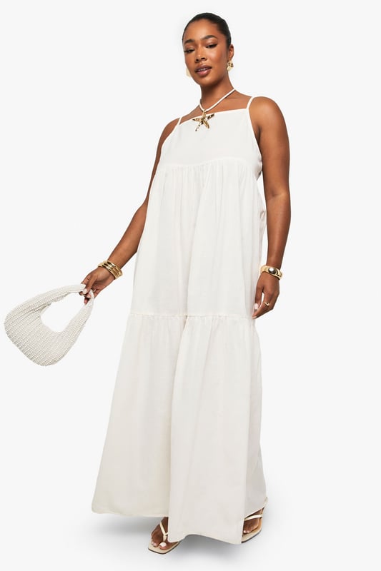 Tiered maxi design with flowing silhouette for effortless movement
        Distinctive strappy neckline with decorative front detail for added interest
        Lightweight linen-look fabric perfect for warm-weather comfort
        Relaxed fit with generous cut through body for all-day ease
        Versatile floor-length style suitable for various casual occasions
    
    This breezy tiered maxi dress captures carefree summer style with its flowing silhouette and distinctive strappy neckline. The decorative front detail adds a touch of bohemian charm, while the lightweight linen-look fabric ensures comfort during warmer days. Style with flat sandals and a mini handbag as shown for daytime gatherings, or customise with layered gold jewellery and espadrilles for alfresco dining. The relaxed fit makes this Boohoo piece ideal for family barbecues, beach outings, or casual weekend brunches. Its neutral versatility allows for endless accessorising options - try adding a denim jacket for cooler evenings or a wide-brimmed hat for garden parties. This plus-size dress combines effortless style with practical comfort for your everyday summer wardrobe.