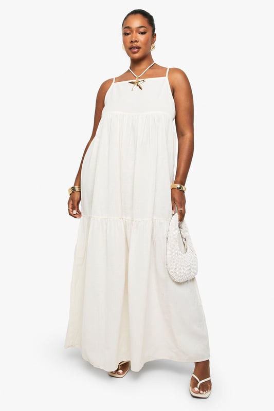 Tiered maxi design with flowing silhouette for effortless movement
        Distinctive strappy neckline with decorative front detail for added interest
        Lightweight linen-look fabric perfect for warm-weather comfort
        Relaxed fit with generous cut through body for all-day ease
        Versatile floor-length style suitable for various casual occasions
    
    This breezy tiered maxi dress captures carefree summer style with its flowing silhouette and distinctive strappy neckline. The decorative front detail adds a touch of bohemian charm, while the lightweight linen-look fabric ensures comfort during warmer days. Style with flat sandals and a mini handbag as shown for daytime gatherings, or customise with layered gold jewellery and espadrilles for alfresco dining. The relaxed fit makes this Boohoo piece ideal for family barbecues, beach outings, or casual weekend brunches. Its neutral versatility allows for endless accessorising options - try adding a denim jacket for cooler evenings or a wide-brimmed hat for garden parties. This plus-size dress combines effortless style with practical comfort for your everyday summer wardrobe.