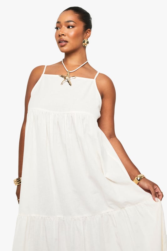 Tiered maxi design with flowing silhouette for effortless movement
        Distinctive strappy neckline with decorative front detail for added interest
        Lightweight linen-look fabric perfect for warm-weather comfort
        Relaxed fit with generous cut through body for all-day ease
        Versatile floor-length style suitable for various casual occasions
    
    This breezy tiered maxi dress captures carefree summer style with its flowing silhouette and distinctive strappy neckline. The decorative front detail adds a touch of bohemian charm, while the lightweight linen-look fabric ensures comfort during warmer days. Style with flat sandals and a mini handbag as shown for daytime gatherings, or customise with layered gold jewellery and espadrilles for alfresco dining. The relaxed fit makes this Boohoo piece ideal for family barbecues, beach outings, or casual weekend brunches. Its neutral versatility allows for endless accessorising options - try adding a denim jacket for cooler evenings or a wide-brimmed hat for garden parties. This plus-size dress combines effortless style with practical comfort for your everyday summer wardrobe.