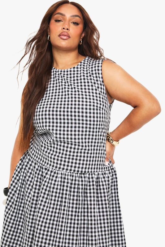 Textured gingham midi dress with a flattering smocked design
        Sleeveless silhouette with a modest round neckline
        Practical side pockets for everyday convenience
        Gathered skirt detail creates a feminine, flowing shape
        Versatile midi length perfect for various seasonal styling
    
    This charming gingham midi dress combines timeless pattern with contemporary design. The smocked detailing creates a flattering silhouette that gently defines the waist before flowing into a beautifully gathered skirt. Style with white kitten heels and a small handbag for family gatherings or weekend brunches. For cooler days, layer with a cropped denim jacket and trainers for an effortlessly casual look. The practical side pockets add functionality to fashion, while the versatile midi length works beautifully across seasons. Perfect for garden parties, casual outings or relaxed office environments, this Boohoo dress offers the ideal balance of comfort and style for the fashion-forward woman who values both trend and wearability.