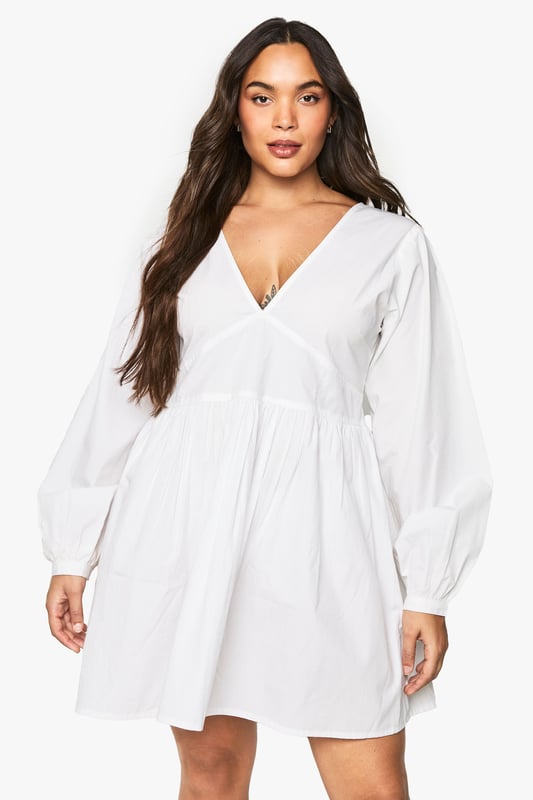 Flattering V-neckline with smocked bodice detail for a comfortable fit
        Voluminous blouson sleeves that create a romantic silhouette
        Open back design with delicate tie fastening for an unexpected twist
        Relaxed A-line shape with gathered skirt for effortless movement
        Versatile mini length perfect for day-to-night styling
    
    This charming cotton smock dress combines comfort with contemporary style. The smocked bodice creates a flattering fit whilst the blouson sleeves add a touch of drama to this otherwise understated piece. The open back with tie detail offers a playful element that's perfect for warmer days. Style with white trainers and a mini handbag for casual daytime outings, as shown on our model. For family gatherings or brunch dates, pair with delicate jewellery and strappy sandals. The relaxed silhouette makes this Boohoo dress a versatile addition to your wardrobe that works beautifully for garden parties, weekend shopping trips, or casual meet-ups with friends. The easy-to-wear design ensures you'll reach for this dress time and again throughout the seasons.