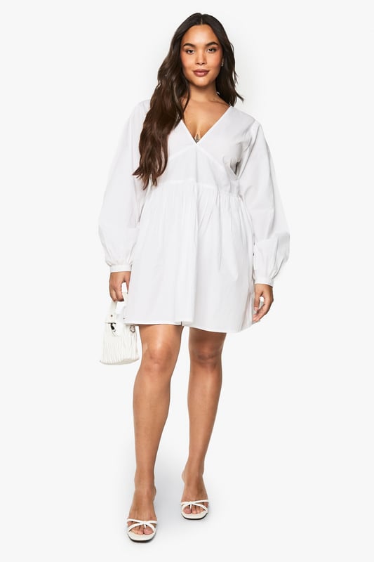 Flattering V-neckline with smocked bodice detail for a comfortable fit
        Voluminous blouson sleeves that create a romantic silhouette
        Open back design with delicate tie fastening for an unexpected twist
        Relaxed A-line shape with gathered skirt for effortless movement
        Versatile mini length perfect for day-to-night styling
    
    This charming cotton smock dress combines comfort with contemporary style. The smocked bodice creates a flattering fit whilst the blouson sleeves add a touch of drama to this otherwise understated piece. The open back with tie detail offers a playful element that's perfect for warmer days. Style with white trainers and a mini handbag for casual daytime outings, as shown on our model. For family gatherings or brunch dates, pair with delicate jewellery and strappy sandals. The relaxed silhouette makes this Boohoo dress a versatile addition to your wardrobe that works beautifully for garden parties, weekend shopping trips, or casual meet-ups with friends. The easy-to-wear design ensures you'll reach for this dress time and again throughout the seasons.