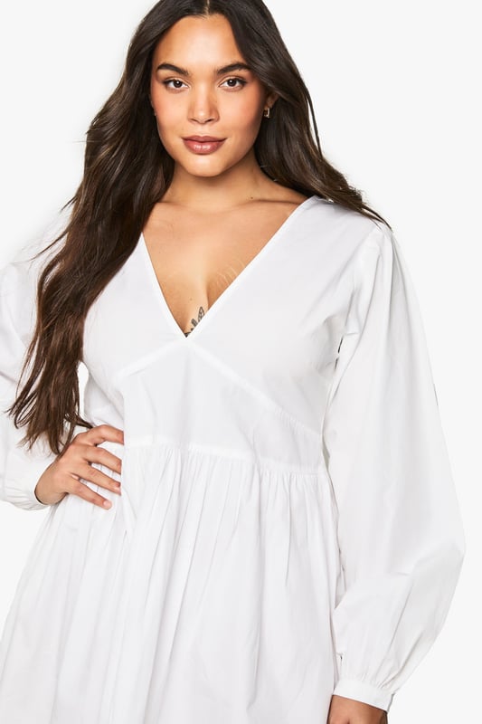 Flattering V-neckline with smocked bodice detail for a comfortable fit
        Voluminous blouson sleeves that create a romantic silhouette
        Open back design with delicate tie fastening for an unexpected twist
        Relaxed A-line shape with gathered skirt for effortless movement
        Versatile mini length perfect for day-to-night styling
    
    This charming cotton smock dress combines comfort with contemporary style. The smocked bodice creates a flattering fit whilst the blouson sleeves add a touch of drama to this otherwise understated piece. The open back with tie detail offers a playful element that's perfect for warmer days. Style with white trainers and a mini handbag for casual daytime outings, as shown on our model. For family gatherings or brunch dates, pair with delicate jewellery and strappy sandals. The relaxed silhouette makes this Boohoo dress a versatile addition to your wardrobe that works beautifully for garden parties, weekend shopping trips, or casual meet-ups with friends. The easy-to-wear design ensures you'll reach for this dress time and again throughout the seasons.