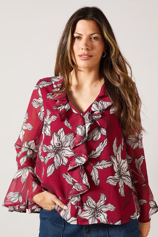 Elegant V-neckline with cascading ruffle detail for a feminine touch
        Striking floral print throughout for a sophisticated daytime look
        Graceful bell sleeves with flared cuffs adding movement and charm
        Lightweight woven fabric offering comfort and easy wearability
        Versatile silhouette that can be styled tucked in or worn loose
    
    This Wallis blouse combines sophistication with effortless style through its beautiful ruffle detailing and eye-catching floral pattern. The flattering V-neckline frames the dcolletage beautifully, while the statement bell sleeves create a graceful silhouette that moves with you. Perfect for daytime occasions, style this versatile piece with wide-leg denim trousers as shown for a casual family lunch, or tuck into a tailored skirt for garden parties. The lightweight fabric ensures all-day comfort without compromising on style. Accessorise with simple gold-toned jewellery and a slouchy tote bag for a complete look that transitions seamlessly from shopping trips to casual gatherings. This blouse offers the glamour and sophistication Wallis is known for while maintaining practicality for everyday wear.