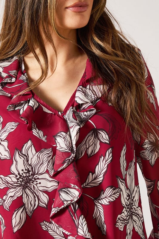 Elegant V-neckline with cascading ruffle detail for a feminine touch
        Striking floral print throughout for a sophisticated daytime look
        Graceful bell sleeves with flared cuffs adding movement and charm
        Lightweight woven fabric offering comfort and easy wearability
        Versatile silhouette that can be styled tucked in or worn loose
    
    This Wallis blouse combines sophistication with effortless style through its beautiful ruffle detailing and eye-catching floral pattern. The flattering V-neckline frames the dcolletage beautifully, while the statement bell sleeves create a graceful silhouette that moves with you. Perfect for daytime occasions, style this versatile piece with wide-leg denim trousers as shown for a casual family lunch, or tuck into a tailored skirt for garden parties. The lightweight fabric ensures all-day comfort without compromising on style. Accessorise with simple gold-toned jewellery and a slouchy tote bag for a complete look that transitions seamlessly from shopping trips to casual gatherings. This blouse offers the glamour and sophistication Wallis is known for while maintaining practicality for everyday wear.