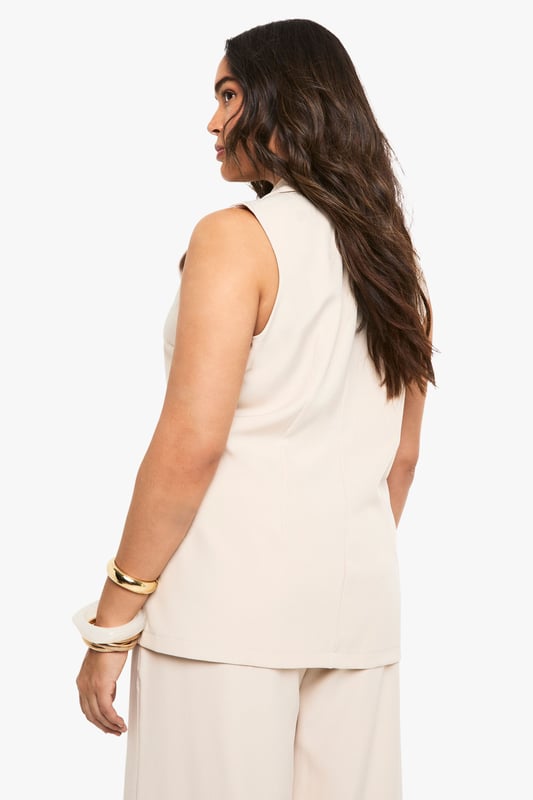Sleeveless design with structured notched lapels for a sophisticated silhouette
        Single button fastening creates a flattering waistline definition
        Practical side pockets perfect for small essentials
        Versatile sleeveless cut ideal for layering or wearing alone
        Tailored fit with clean lines that complement curves beautifully
    
    This sleeveless blazer from Boohoo brings contemporary flair to your wardrobe staples. The clean-cut design offers endless styling possibilities-pair with the matching wide-leg trousers as seen on our model for a coordinated ensemble that works brilliantly for casual gatherings. For daytime outings, layer over a fitted tee with your favourite jeans and trainers. The sleeveless silhouette makes this piece particularly adaptable for transitional weather, allowing you to showcase statement jewellery while maintaining a polished appearance. For family gatherings, style with a silky camisole underneath and add metallic accessories for a touch of understated glamour. The versatile nature of this blazer ensures it will become a cornerstone in your capsule wardrobe, effortlessly taking you from casual brunches to smart-casual evening events with simple styling adjustments.
