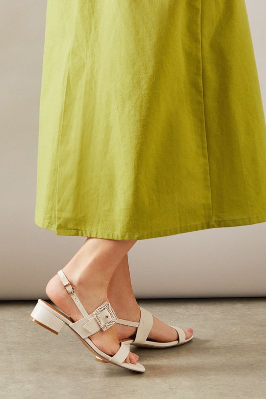 Stylish slingback design with adjustable buckle fastening for a secure fit
        Distinctive raffia-textured buckle detail adds a touch of artisanal flair
        Comfortable low block heel measuring between 2.5-4.5cm for all-day wearability
        Clean-lined silhouette with minimalist strap detailing for versatile styling
        Faux leather construction offers a sophisticated finish with practical durability
    
    The Raelynn sandals from Wallis present the perfect balance of comfort and sophistication for your daytime wardrobe. The thoughtfully designed low block heel provides stability whilst the slingback style with its distinctive raffia buckle detail adds a touch of textural interest to any ensemble. These versatile sandals pair beautifully with flowing midi dresses as shown, but work equally well with tailored trousers or casual denim. Ideal for garden parties, weekend brunches or casual family gatherings where you want to look polished without sacrificing comfort. The neutral tone makes these an excellent investment piece that will complement numerous outfits throughout the warmer months. For a coordinated daytime look, match with a structured handbag and delicate jewellery to showcase your sophisticated yet relaxed style.