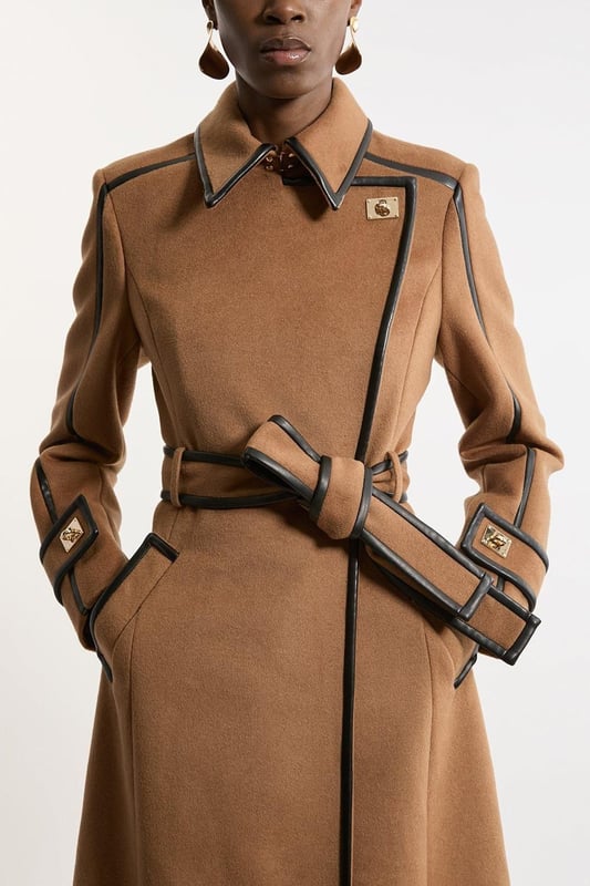 Fall '24: Allow our latest collection of autumn pieces to inspire you for the season ahead. Feel elevated no matter the weather in our midi length coat, made in high quality, thick wool, featuring a fit that flatters the figure and faux leather trims. Wear it over any outfit, whether heading out for dinner or to the office. Wool Blend Faux Leather Trim Belted Tailored Coat High Quality Wool Blend Fabric Flattering Fitted Bodice Straight Hanging Skirt Metallic Clasp Buttons at Collar and Cuffs High, Collared Neckline Belted Waistline Unique, Faux Leather TrimsShop this seasons belted coats and jackets or browse the full collection of coats and jackets now.