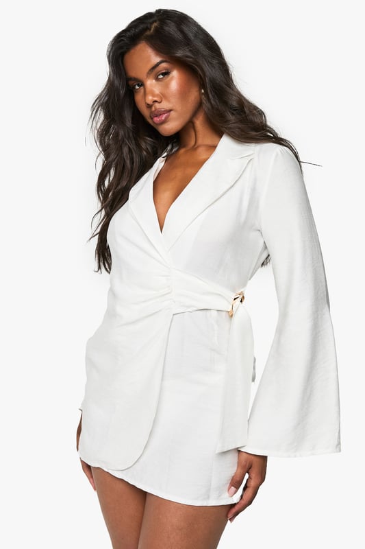 Tailored blazer dress with wrap neckline
        Linen-look fabric for a textured appearance
        Buckle detail adds a touch of sophistication
        Tie waist for a flattering silhouette
        Long sleeves with a structured shoulder
    
    Make a statement in this chic linen-look blazer dress, perfect for those nights out when you want to turn heads. The wrap neckline and tie waist create a figure-hugging silhouette that's both flattering and comfortable. The buckle detail adds an element of intrigue, while the tailored structure gives a polished look. Style it with strappy heels and statement earrings for a night at the club, or dress it down with white trainers for drinks with friends. The versatility of this piece makes it a wardrobe essential for the fashion-forward woman who values both style and comfort. Whether you're dancing the night away or enjoying cocktails at a rooftop bar, this blazer dress is sure to keep you looking effortlessly stylish.