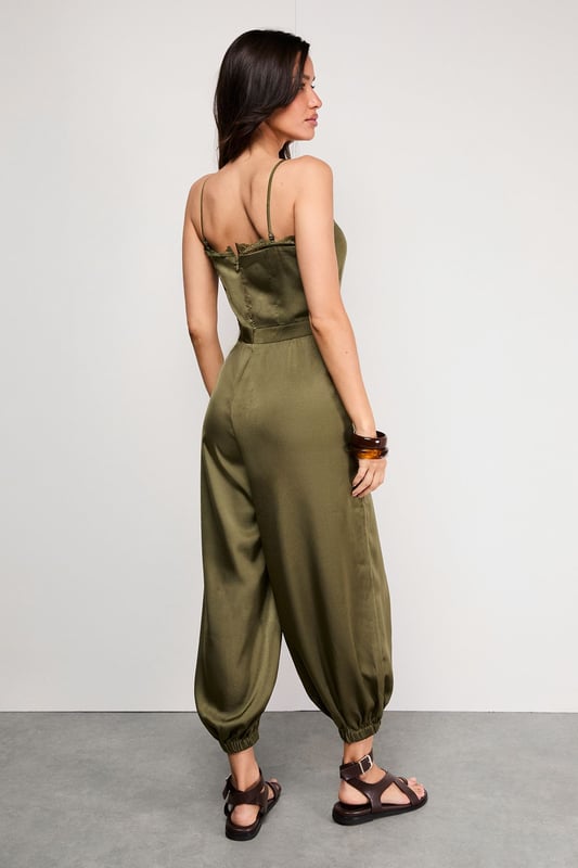 Delicate lace trim along the neckline adds a feminine touch to this satin jumpsuit
        Adjustable strappy design ensures a comfortable, personalised fit
        Elasticated cuffs create a distinctive balloon silhouette for the legs
        Relaxed fit through the body offers effortless movement and comfort
        Petite sizing ensures the perfect proportions for smaller frames
    
    This Warehouse satin jumpsuit combines casual comfort with sophisticated style. The lustrous fabric catches the light beautifully whilst the elasticated cuffs create a fashionable balloon silhouette that's both on-trend and flattering. Perfect for daytime gatherings, style with flat strappy sandals and wooden bangles for a relaxed garden party or family lunch. For cooler evenings, layer with an oversized denim jacket and switch to ankle boots. The versatile design transitions seamlessly from casual brunches to evening drinks - simply add statement earrings and a clutch bag to transform your look. The adjustable straps allow you to customise the fit, making this jumpsuit a wardrobe essential that works hard for your everyday style.