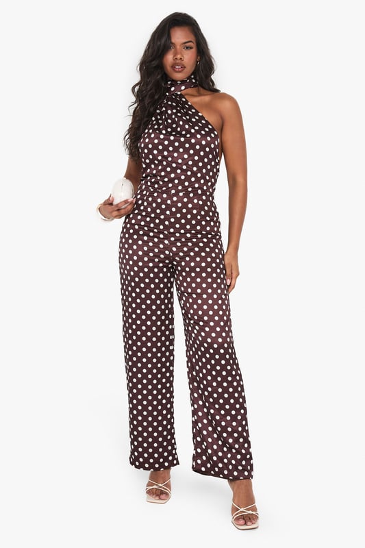 Striking polka dot satin jumpsuit with elegant high neck design
        Sophisticated scarf detail adds dramatic flair to the neckline
        Flattering wide-leg silhouette for effortless movement
        Statement open back design for head-turning appeal
        Perfect one-piece solution for special occasions with minimal styling required
    
    Make a striking entrance at your next formal event in this captivating polka dot satin jumpsuit from Boohoo. The distinctive high neck with scarf detail creates a sophisticated focal point, while the open back adds a touch of allure. The wide-leg cut offers both comfort and elegance, creating a flowing silhouette that moves beautifully as you walk. Style with metallic strappy heels as shown for a refined evening look, and add statement earrings to complement the neckline. This versatile piece transitions seamlessly from weddings to graduation ceremonies and race day events. For cooler evenings, layer with a tailored blazer or delicate wrap to maintain the jumpsuit's elegant profile whilst adding warmth.