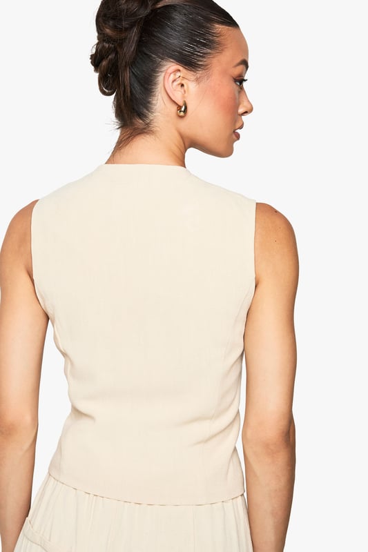 Sleeveless waistcoat with linen-look texture for a relaxed yet refined aesthetic
        V-neckline and button-through front with contrasting buttons for added visual interest
        Tailored fit designed specifically for taller frames, offering proper proportions
        Practical front pockets perfect for small essentials or a casual hand placement
        Versatile layering piece that transitions effortlessly between seasons
    
    This linen-look waistcoat brings a touch of understated sophistication to your wardrobe. Designed with the taller frame in mind, it offers the perfect proportions for a flattering silhouette. Style it as seen with relaxed denim jeans for an effortlessly cool daytime look, or pair with tailored trousers and a crisp shirt for more formal occasions. The neutral tone makes it incredibly versatile - layer under a blazer during cooler months or wear alone with statement jewellery when temperatures rise. Perfect for family gatherings, casual office environments, or weekend brunches, this Boohoo waistcoat can be customised to suit your personal style. The textured fabric adds dimension to any outfit whilst maintaining a comfortable, breathable feel that's ideal for all-day wear.