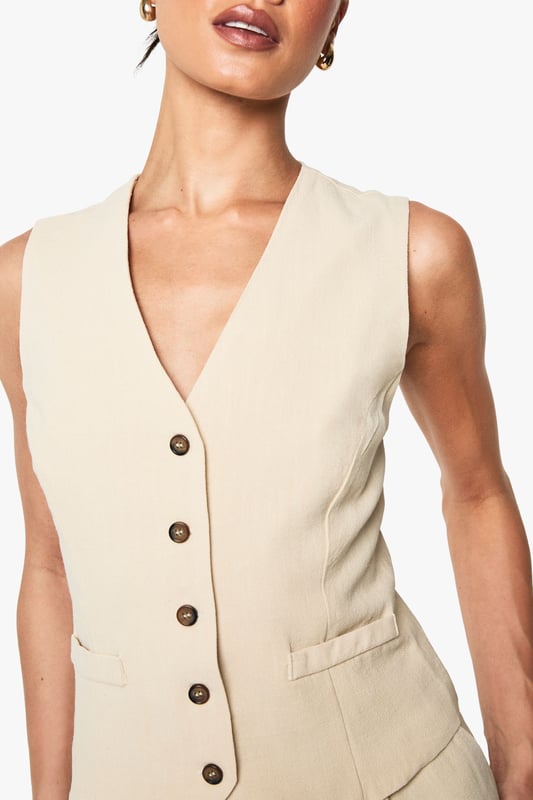 Sleeveless waistcoat with linen-look texture for a relaxed yet refined aesthetic
        V-neckline and button-through front with contrasting buttons for added visual interest
        Tailored fit designed specifically for taller frames, offering proper proportions
        Practical front pockets perfect for small essentials or a casual hand placement
        Versatile layering piece that transitions effortlessly between seasons
    
    This linen-look waistcoat brings a touch of understated sophistication to your wardrobe. Designed with the taller frame in mind, it offers the perfect proportions for a flattering silhouette. Style it as seen with relaxed denim jeans for an effortlessly cool daytime look, or pair with tailored trousers and a crisp shirt for more formal occasions. The neutral tone makes it incredibly versatile - layer under a blazer during cooler months or wear alone with statement jewellery when temperatures rise. Perfect for family gatherings, casual office environments, or weekend brunches, this Boohoo waistcoat can be customised to suit your personal style. The textured fabric adds dimension to any outfit whilst maintaining a comfortable, breathable feel that's ideal for all-day wear.