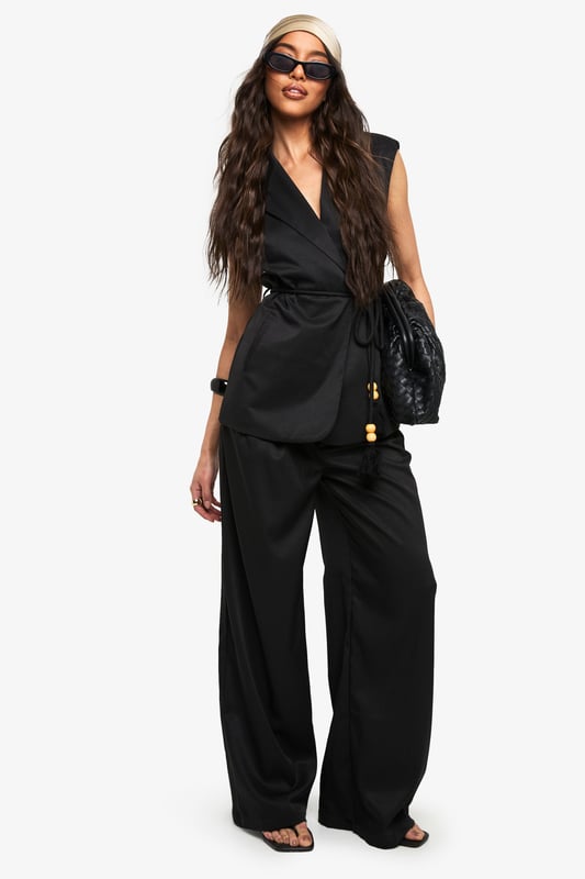 Sleeveless wrap waistcoat with sophisticated lapel detailing
        Flattering loose fit design for effortless movement
        Stylish belt with decorative wooden bead accents
        Linen-look texture adding dimension to your outfit
        Versatile layering piece suitable for multiple seasons
    
    This chic waistcoat combines contemporary styling with timeless appeal. The wrap design creates a flattering silhouette while the loose fit ensures comfort for all-day wear. Style with the coordinating wide-leg trousers as seen on our model for a polished co-ord look that's perfect for casual gatherings. For daytime outings, pair with your favourite denim and trainers, adding statement sunglasses for a touch of glamour. When evening approaches, transform your look by layering over a fitted top and accessorising with a structured handbag. The belt with wooden bead detailing adds a distinctive finishing touch that draws the eye and defines the waist. This versatile piece transitions seamlessly from family brunches to casual meetups, embodying boohoo's commitment to inclusive, trend-focused fashion that works for every occasion.