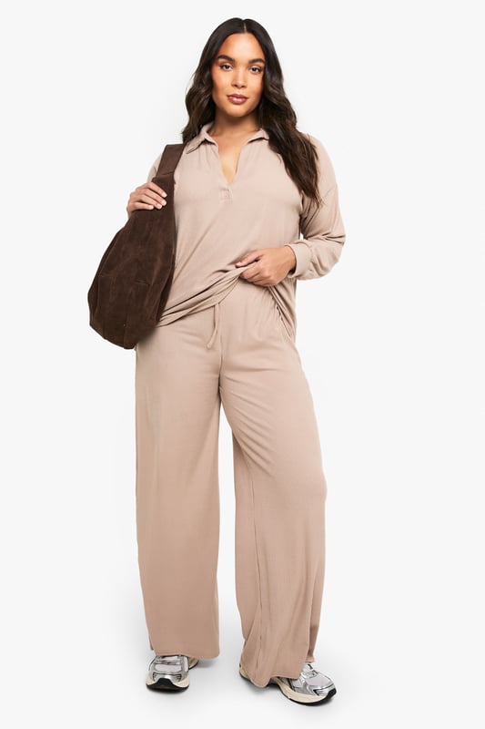 Ribbed texture for added comfort and visual interest
        Collared neckline with open V-front for a relaxed yet polished look
        Wide-leg trousers with flowing silhouette for unrestricted movement
        Long sleeves with comfortable cuffed finish
        Coordinated two-piece set for effortless styling
    
    This sophisticated loungewear set from Boohoo combines comfort with contemporary style. The ribbed collared top features a flattering V-neckline that adds a touch of refinement to your at-home wardrobe, while the wide-leg trousers create a fluid silhouette that moves beautifully with you. Perfect for those lazy Sunday mornings with a coffee and magazine, yet smart enough for impromptu video calls or welcoming unexpected visitors. Style with trainers as seen on our model for quick errands, or swap for plush slippers when embracing total relaxation. The versatile design works wonderfully layered with an oversized cardigan when temperatures drop, or simply on its own for warmer days. This set represents the ultimate balance between comfort and put-together style for the fashion-conscious homebody.