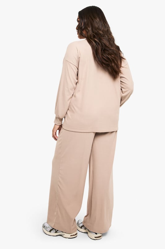 Ribbed texture for added comfort and visual interest
        Collared neckline with open V-front for a relaxed yet polished look
        Wide-leg trousers with flowing silhouette for unrestricted movement
        Long sleeves with comfortable cuffed finish
        Coordinated two-piece set for effortless styling
    
    This sophisticated loungewear set from Boohoo combines comfort with contemporary style. The ribbed collared top features a flattering V-neckline that adds a touch of refinement to your at-home wardrobe, while the wide-leg trousers create a fluid silhouette that moves beautifully with you. Perfect for those lazy Sunday mornings with a coffee and magazine, yet smart enough for impromptu video calls or welcoming unexpected visitors. Style with trainers as seen on our model for quick errands, or swap for plush slippers when embracing total relaxation. The versatile design works wonderfully layered with an oversized cardigan when temperatures drop, or simply on its own for warmer days. This set represents the ultimate balance between comfort and put-together style for the fashion-conscious homebody.