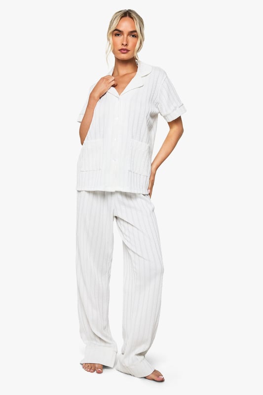 Elegant pointelle knitted fabric with delicate textured pattern throughout
        Classic collared shirt design with short sleeves for comfort
        Relaxed fit trousers with wide-leg silhouette for effortless movement
        Practical front pockets on the shirt for added functionality
        Coordinated two-piece set designed specifically for bridal occasions
    
    This sophisticated Pointelle Short Sleeve Shirt and Trouser Set from Boohoo offers the perfect balance of comfort and style for your special bridal moments. The textured knitted fabric creates a subtle yet distinctive pattern that catches the light beautifully, whilst the classic shirt design with its neat collar presents a refined silhouette. The wide-leg trousers flow gracefully with every movement, creating an air of relaxed elegance. Perfect for bridal preparation photos or post-ceremony relaxation, this set can be styled with delicate jewellery and soft slippers for a morning-of-the-wedding look. Alternatively, pair with elegant flat sandals and a loose braid for a honeymoon breakfast ensemble that radiates newlywed bliss. The versatile design ensures you'll treasure this set long after your wedding celebrations.