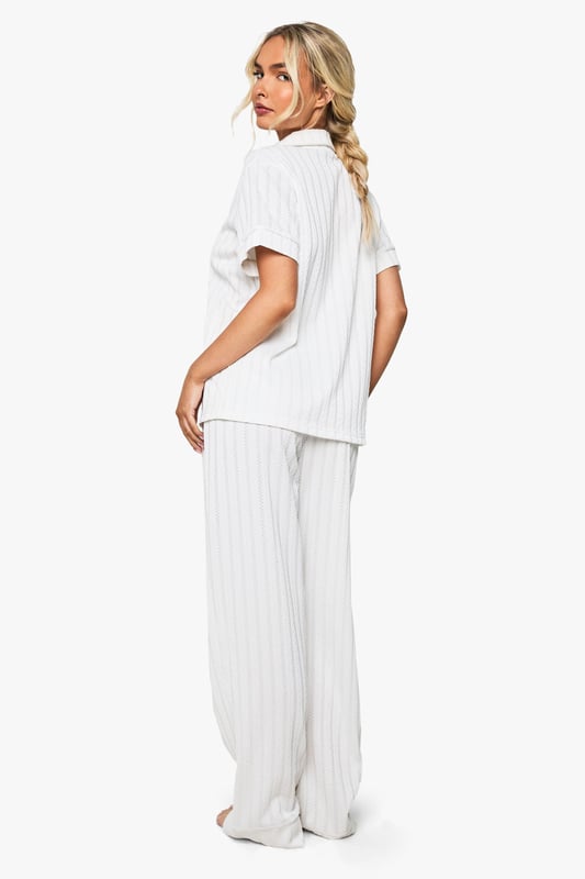Elegant pointelle knitted fabric with delicate textured pattern throughout
        Classic collared shirt design with short sleeves for comfort
        Relaxed fit trousers with wide-leg silhouette for effortless movement
        Practical front pockets on the shirt for added functionality
        Coordinated two-piece set designed specifically for bridal occasions
    
    This sophisticated Pointelle Short Sleeve Shirt and Trouser Set from Boohoo offers the perfect balance of comfort and style for your special bridal moments. The textured knitted fabric creates a subtle yet distinctive pattern that catches the light beautifully, whilst the classic shirt design with its neat collar presents a refined silhouette. The wide-leg trousers flow gracefully with every movement, creating an air of relaxed elegance. Perfect for bridal preparation photos or post-ceremony relaxation, this set can be styled with delicate jewellery and soft slippers for a morning-of-the-wedding look. Alternatively, pair with elegant flat sandals and a loose braid for a honeymoon breakfast ensemble that radiates newlywed bliss. The versatile design ensures you'll treasure this set long after your wedding celebrations.