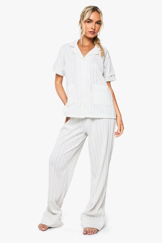 Elegant pointelle knitted fabric with delicate textured pattern throughout
        Classic collared shirt design with short sleeves for comfort
        Relaxed fit trousers with wide-leg silhouette for effortless movement
        Practical front pockets on the shirt for added functionality
        Coordinated two-piece set designed specifically for bridal occasions
    
    This sophisticated Pointelle Short Sleeve Shirt and Trouser Set from Boohoo offers the perfect balance of comfort and style for your special bridal moments. The textured knitted fabric creates a subtle yet distinctive pattern that catches the light beautifully, whilst the classic shirt design with its neat collar presents a refined silhouette. The wide-leg trousers flow gracefully with every movement, creating an air of relaxed elegance. Perfect for bridal preparation photos or post-ceremony relaxation, this set can be styled with delicate jewellery and soft slippers for a morning-of-the-wedding look. Alternatively, pair with elegant flat sandals and a loose braid for a honeymoon breakfast ensemble that radiates newlywed bliss. The versatile design ensures you'll treasure this set long after your wedding celebrations.