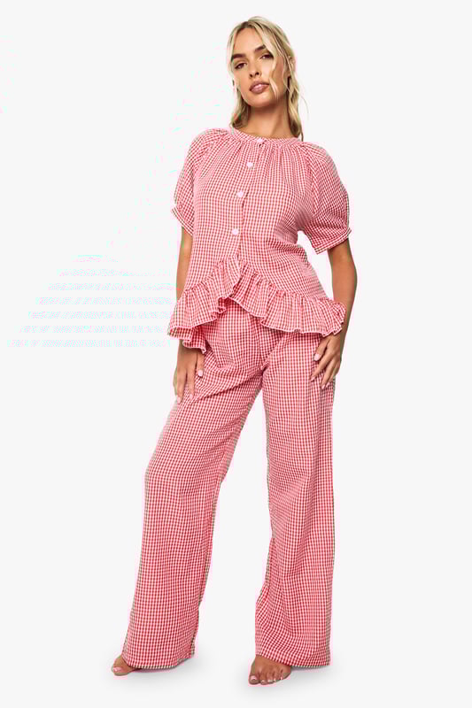 Oversized fit shirt with charming gingham pattern throughout
        Playful frill detail trim adds a feminine touch to the design
        Button-through front for easy wear and styling versatility
        Short sleeves with gentle gathering for a relaxed silhouette
        Wide-leg trousers with comfortable waistband for unrestricted movement
    
    Transform your nightwear collection with this delightfully charming gingham pyjama set from Boohoo. The oversized shirt features a gathered neckline and sweet frill detailing that adds a touch of playfulness to your evening routine. The relaxed short sleeves and button-through design ensure comfort without compromising on style. Paired with the matching wide-leg trousers, this set offers the perfect balance of comfort and fashion-forward design. Ideal for lounging at home on lazy weekend mornings or settling in for a cosy night of films and snacks. Complete your nighttime ensemble with fluffy slippers and a warm dressing gown during colder months, or wear the pieces separately to mix and match with your existing nightwear collection for versatile styling options throughout the seasons.