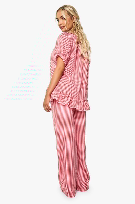 Oversized fit shirt with charming gingham pattern throughout
        Playful frill detail trim adds a feminine touch to the design
        Button-through front for easy wear and styling versatility
        Short sleeves with gentle gathering for a relaxed silhouette
        Wide-leg trousers with comfortable waistband for unrestricted movement
    
    Transform your nightwear collection with this delightfully charming gingham pyjama set from Boohoo. The oversized shirt features a gathered neckline and sweet frill detailing that adds a touch of playfulness to your evening routine. The relaxed short sleeves and button-through design ensure comfort without compromising on style. Paired with the matching wide-leg trousers, this set offers the perfect balance of comfort and fashion-forward design. Ideal for lounging at home on lazy weekend mornings or settling in for a cosy night of films and snacks. Complete your nighttime ensemble with fluffy slippers and a warm dressing gown during colder months, or wear the pieces separately to mix and match with your existing nightwear collection for versatile styling options throughout the seasons.