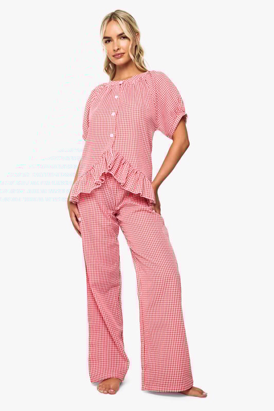 Oversized fit shirt with charming gingham pattern throughout
        Playful frill detail trim adds a feminine touch to the design
        Button-through front for easy wear and styling versatility
        Short sleeves with gentle gathering for a relaxed silhouette
        Wide-leg trousers with comfortable waistband for unrestricted movement
    
    Transform your nightwear collection with this delightfully charming gingham pyjama set from Boohoo. The oversized shirt features a gathered neckline and sweet frill detailing that adds a touch of playfulness to your evening routine. The relaxed short sleeves and button-through design ensure comfort without compromising on style. Paired with the matching wide-leg trousers, this set offers the perfect balance of comfort and fashion-forward design. Ideal for lounging at home on lazy weekend mornings or settling in for a cosy night of films and snacks. Complete your nighttime ensemble with fluffy slippers and a warm dressing gown during colder months, or wear the pieces separately to mix and match with your existing nightwear collection for versatile styling options throughout the seasons.