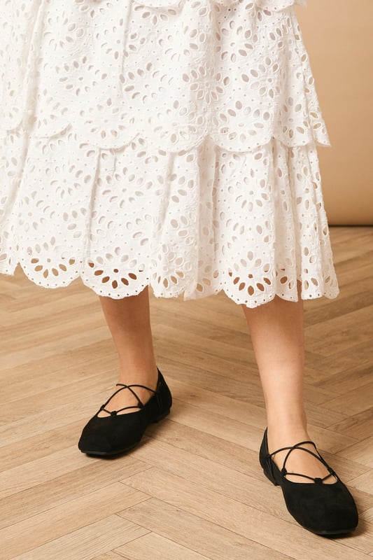 Intricate broderie anglaise detailing with floral eyelet pattern throughout
        Elegant tiered design creates beautiful movement and dimension
        Midi length falls gracefully below the knee for a feminine silhouette
        Scalloped hem adds a delicate finishing touch to each tier
        High-waisted fit accentuates the natural waistline
    
    This charming broderie tiered midi skirt from Oasis combines timeless femininity with contemporary styling. The delicate eyelet pattern creates a romantic texture that catches the light beautifully as you move, while the tiered construction adds playful volume and flow. Style with a denim waistcoat as shown for a balanced casual look, or pair with a fitted blouse for garden parties and family gatherings. The versatile midi length works wonderfully with both ankle boots for cooler days or flat sandals when the temperature rises. This skirt transitions effortlessly from daytime outings to casual evening events - simply switch your accessories to refresh your look. The high-waisted design flatters your figure whilst providing comfort for all-day wear.