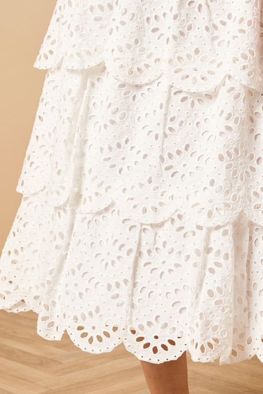 Intricate broderie anglaise detailing with floral eyelet pattern throughout
        Elegant tiered design creates beautiful movement and dimension
        Midi length falls gracefully below the knee for a feminine silhouette
        Scalloped hem adds a delicate finishing touch to each tier
        High-waisted fit accentuates the natural waistline
    
    This charming broderie tiered midi skirt from Oasis combines timeless femininity with contemporary styling. The delicate eyelet pattern creates a romantic texture that catches the light beautifully as you move, while the tiered construction adds playful volume and flow. Style with a denim waistcoat as shown for a balanced casual look, or pair with a fitted blouse for garden parties and family gatherings. The versatile midi length works wonderfully with both ankle boots for cooler days or flat sandals when the temperature rises. This skirt transitions effortlessly from daytime outings to casual evening events - simply switch your accessories to refresh your look. The high-waisted design flatters your figure whilst providing comfort for all-day wear.