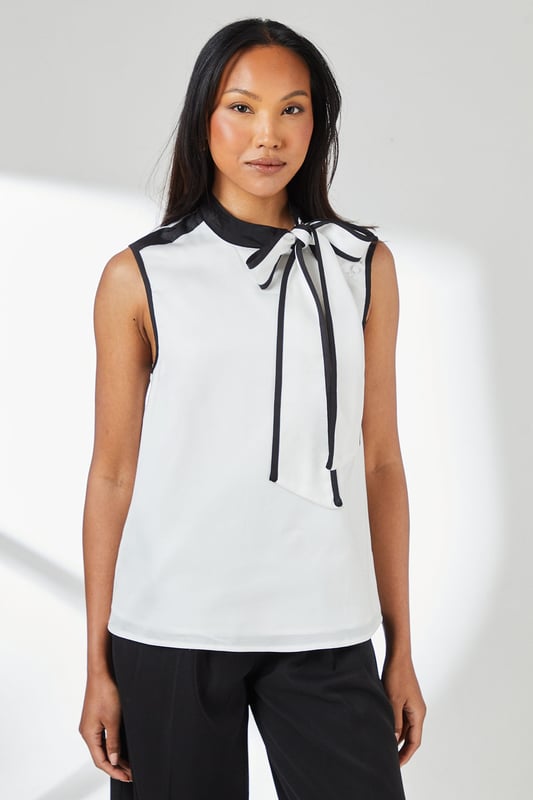 Sleeveless satin top with striking contrast trim along the neckline and armholes
        Elegant tie-neck detail creates a sophisticated bow at the collar
        High neckline offers a refined silhouette perfect for formal settings
        Clean, straight-cut hemline for a polished finish
        Smooth woven fabric with a subtle lustre for an elegant appearance
    
    This Principles sleeveless top combines timeless elegance with contemporary design through its distinctive contrast detailing. The sophisticated tie-neck feature allows for versatile styling-wear it neatly tied for formal occasions or slightly loosened for a more relaxed interpretation. Pair with wide-leg trousers as shown for a chic monochromatic ensemble that transitions seamlessly from office to evening events. For formal occasions, style with a tailored blazer, statement earrings and court shoes. Alternatively, create a smart-casual look by teaming with slim-fit trousers and pointed flats. The clean lines and classic contrast colouring make this top an excellent foundation piece for multiple outfits, whether attending a wedding reception, business meeting, or sophisticated dinner engagement.