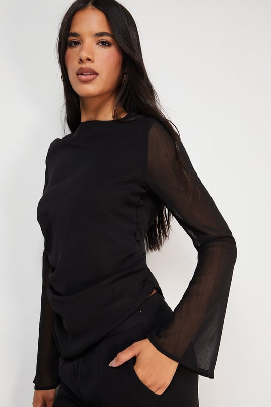 Elegant chiffon top featuring a sophisticated asymmetric design
        Flattering gathered waist detail creates a feminine silhouette
        Sheer long sleeves add a touch of subtle allure
        Versatile boat neckline frames the dcolletage beautifully
        Fully lined body ensures comfort and proper coverage
    
    This Warehouse chiffon top combines contemporary design with effortless wearability. The asymmetric gathering at the waist creates a flattering drape that complements your natural shape, whilst the sheer sleeves add a delicate contrast to the lined body. Style with wide-leg trousers as shown for a sophisticated daytime look, or dress up with tailored cigarette trousers and statement earrings for evening drinks. The versatile design transitions seamlessly from office to weekend brunch, making it a wardrobe essential for the modern British woman. For casual family gatherings, pair with your favourite denim and ballet flats, or dress it up with a sleek blazer and heeled boots for dinner dates. Machine washable for practical everyday wear.