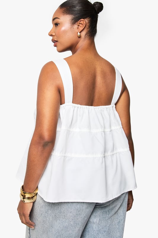 Wide shoulder straps for comfortable all-day wear
        Tiered design with ruched detailing for added texture and dimension
        Front tie detail with delicate drawstrings for adjustable styling
        Relaxed peplum hem creating a flattering silhouette
        Square neckline offering a contemporary, feminine touch
    
    This charming cami top combines comfort with effortless style for your casual wardrobe. The tiered design creates visual interest whilst the ruched detailing adds a touch of playfulness to your look. Style with light-wash denim jeans as shown for a relaxed daytime ensemble, or pair with tailored trousers for a smart-casual finish. The adjustable tie details allow you to customise the fit to your preference, making it ideal for family gatherings or weekend brunches. Accessorise with gold-toned jewellery to enhance the laid-back yet put-together aesthetic. Perfect for the warmer months, this versatile Boohoo piece transitions seamlessly from day to evening with a simple change of accessories - swap your trainers for espadrilles and add a crossbody bag for an effortless summer look.