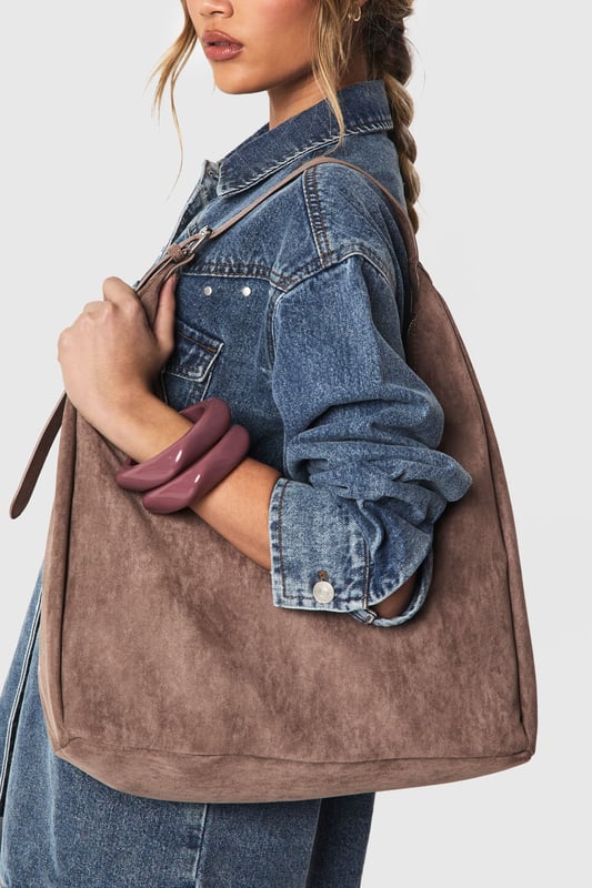 Soft faux suede shoulder bag with a spacious hobo silhouette
        Single adjustable shoulder strap for comfortable carrying
        Roomy interior perfect for everyday essentials
        Minimalist design with clean lines and no external embellishments
        Versatile shape that complements both casual and smart-casual outfits
    
    This faux suede shoulder bag combines practicality with effortless style. The slouchy hobo design offers ample space for your daily necessities whilst maintaining a relaxed aesthetic that works brilliantly with your everyday wardrobe. As shown, pair with denim for a classic daytime look, or match with floaty dresses and ankle boots for weekend brunches. The neutral tone makes it an ideal companion for autumn/winter layering or spring transitional outfits. Perfect for shopping trips, coffee dates or casual workdays, this Boohoo bag strikes the balance between functionality and fashion. The minimalist design ensures it won't compete with your outfit but rather complement it, making this an essential addition to your accessories collection that will serve you season after season.