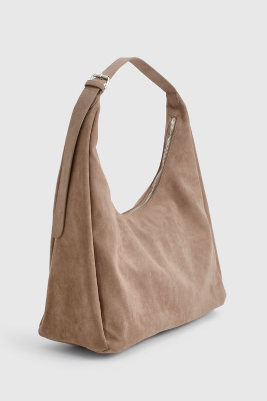 Soft faux suede shoulder bag with a spacious hobo silhouette
        Single adjustable shoulder strap for comfortable carrying
        Roomy interior perfect for everyday essentials
        Minimalist design with clean lines and no external embellishments
        Versatile shape that complements both casual and smart-casual outfits
    
    This faux suede shoulder bag combines practicality with effortless style. The slouchy hobo design offers ample space for your daily necessities whilst maintaining a relaxed aesthetic that works brilliantly with your everyday wardrobe. As shown, pair with denim for a classic daytime look, or match with floaty dresses and ankle boots for weekend brunches. The neutral tone makes it an ideal companion for autumn/winter layering or spring transitional outfits. Perfect for shopping trips, coffee dates or casual workdays, this Boohoo bag strikes the balance between functionality and fashion. The minimalist design ensures it won't compete with your outfit but rather complement it, making this an essential addition to your accessories collection that will serve you season after season.