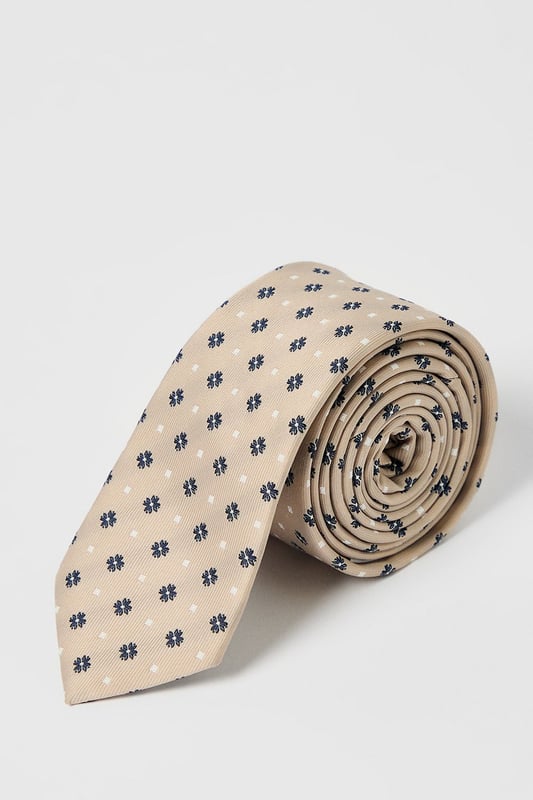 Classic foulard pattern tie with geometric motif for timeless appeal
        Standard width design suitable for both modern and traditional suit styles
        Smooth finish for comfortable all-day wear
        Neat pointed tip with branded lining detail
        Authentic Burton label for quality assurance
    
    This sophisticated foulard tie brings understated elegance to any outfit. The repeating geometric pattern creates visual interest without overwhelming your look, making it perfect for various occasions. Pair with a crisp white shirt and navy blazer for family gatherings or weekend brunches. For casual office days, match with a light blue Oxford shirt and chinos. The versatile design works brilliantly with both plain and subtly patterned shirts, allowing you to create numerous combinations from your existing wardrobe. This Burton tie offers the perfect balance between formal and relaxed styling - ideal for the man who appreciates classic accessories that transition effortlessly from day to evening events. Whether you're heading to the pub with friends or attending a casual wedding, this tie adds a refined finishing touch.