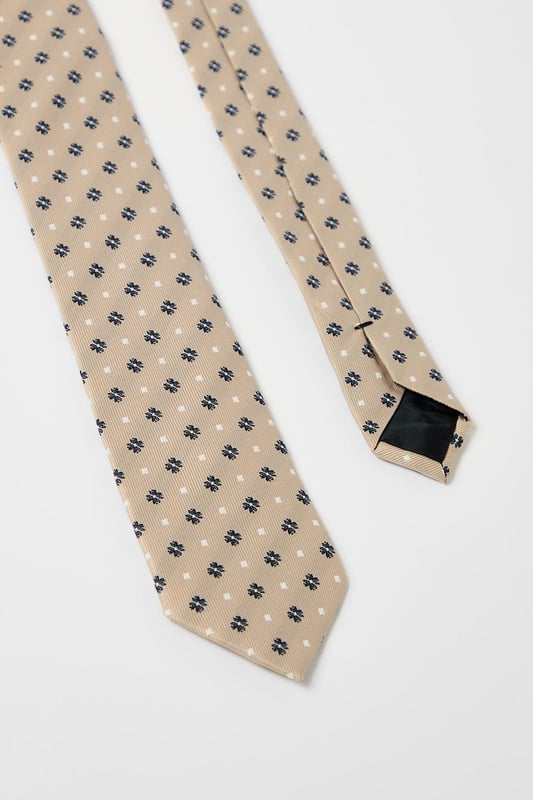 Classic foulard pattern tie with geometric motif for timeless appeal
        Standard width design suitable for both modern and traditional suit styles
        Smooth finish for comfortable all-day wear
        Neat pointed tip with branded lining detail
        Authentic Burton label for quality assurance
    
    This sophisticated foulard tie brings understated elegance to any outfit. The repeating geometric pattern creates visual interest without overwhelming your look, making it perfect for various occasions. Pair with a crisp white shirt and navy blazer for family gatherings or weekend brunches. For casual office days, match with a light blue Oxford shirt and chinos. The versatile design works brilliantly with both plain and subtly patterned shirts, allowing you to create numerous combinations from your existing wardrobe. This Burton tie offers the perfect balance between formal and relaxed styling - ideal for the man who appreciates classic accessories that transition effortlessly from day to evening events. Whether you're heading to the pub with friends or attending a casual wedding, this tie adds a refined finishing touch.
