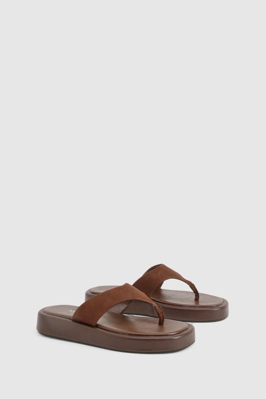Wide fit design for enhanced comfort and all-day wearability
        Chunky platform sole with flat heel (under 2cm) for added height without sacrificing stability
        Faux suede toe post strap with soft finish for reduced friction
        Cushioned footbed providing support for extended wear
        Durable thermoplastic sole offering excellent grip on various surfaces
    
    These wide fit chunky flip-flops combine contemporary style with practical comfort. The faux suede upper creates a textural contrast against the substantial platform sole, making them a versatile addition to your summer wardrobe. Perfect for casual outings, pair them with flowing maxi dresses and oversized sunglasses for beach days, or style with cropped linen trousers and a simple tee for weekend brunches. Their comfortable design makes them ideal for city explorations or garden gatherings when the weather warms. The neutral tone works effortlessly with both vibrant prints and muted ensembles, while the wide fit ensures comfort for all foot shapes. These Boohoo flip-flops offer the perfect blend of on-trend styling and practical design for the fashion-conscious woman seeking both comfort and style this season.