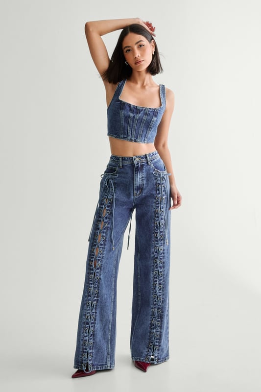 Striking lace-up detail along the sides
        High-waisted design for a flattering silhouette
        Wide-leg cut for a trendy, relaxed look
        Cropped top with square neckline and thick straps
        Back lace-up closure on the top for adjustable fit
    
    Make a bold statement with these eye-catching jeans from NastyGal. The standout lace-up detail running along the sides adds a daring edge to your casual ensemble. Pair with the matching cropped top for a coordinated look that's sure to turn heads. The high-waisted, wide-leg cut is perfect for creating a long, lean silhouette. Style with chunky trainers for a laid-back vibe, or dress up with heeled boots for evening drinks. These versatile jeans are ideal for family gatherings, brunches with friends, or casual Friday at the office. The denim fabric offers comfort and durability, making these jeans a wardrobe staple you'll reach for time and time again.