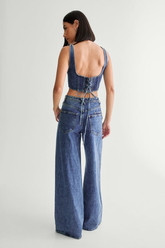 Striking lace-up detail along the sides
        High-waisted design for a flattering silhouette
        Wide-leg cut for a trendy, relaxed look
        Cropped top with square neckline and thick straps
        Back lace-up closure on the top for adjustable fit
    
    Make a bold statement with these eye-catching jeans from NastyGal. The standout lace-up detail running along the sides adds a daring edge to your casual ensemble. Pair with the matching cropped top for a coordinated look that's sure to turn heads. The high-waisted, wide-leg cut is perfect for creating a long, lean silhouette. Style with chunky trainers for a laid-back vibe, or dress up with heeled boots for evening drinks. These versatile jeans are ideal for family gatherings, brunches with friends, or casual Friday at the office. The denim fabric offers comfort and durability, making these jeans a wardrobe staple you'll reach for time and time again.