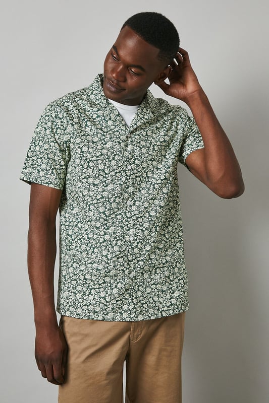 Distinctive revere collar design for a relaxed, open neckline aesthetic
        All-over floral print pattern adding visual interest and seasonal charm
        Short sleeve construction perfect for warmer weather comfort
        Cotton fabric offering breathable wear throughout the day
        Versatile regular fit that suits various body types
    
    This Maine floral print revere shirt brings a refreshing twist to casual dressing. The eye-catching pattern creates a focal point for any outfit, while the comfortable cotton construction ensures all-day wearability. Style as seen on our model with neutral chino shorts and crisp white trainers for an effortlessly cool summer look. For evening socials, pair with slim-fit trousers and loafers to transition seamlessly from day to night. The revere collar adds a touch of laid-back sophistication that works brilliantly for garden parties, weekend brunches or holiday getaways. This shirt can be worn buttoned up or open over a plain t-shirt for two distinct styling options, making it a versatile addition to your warm-weather wardrobe. Perfect for those seeking to inject personality into their casual collection.