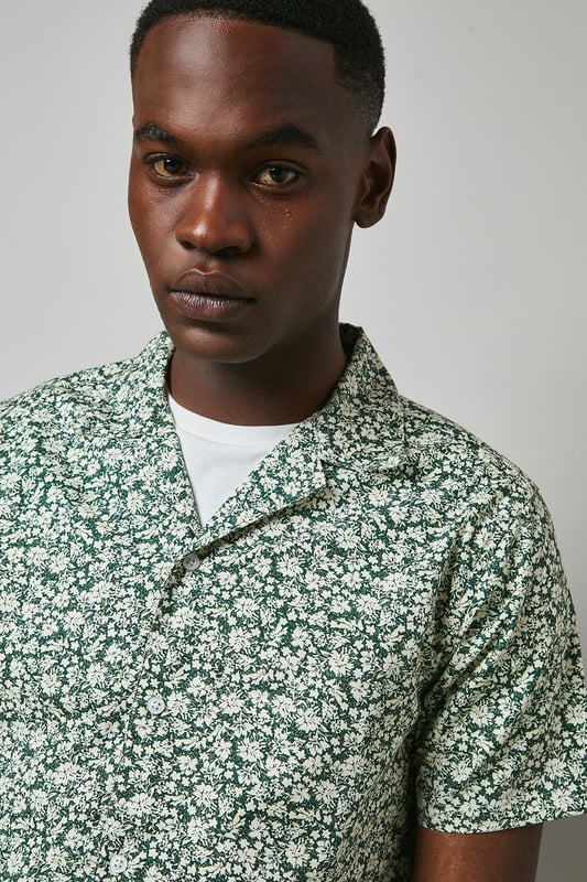 Distinctive revere collar design for a relaxed, open neckline aesthetic
        All-over floral print pattern adding visual interest and seasonal charm
        Short sleeve construction perfect for warmer weather comfort
        Cotton fabric offering breathable wear throughout the day
        Versatile regular fit that suits various body types
    
    This Maine floral print revere shirt brings a refreshing twist to casual dressing. The eye-catching pattern creates a focal point for any outfit, while the comfortable cotton construction ensures all-day wearability. Style as seen on our model with neutral chino shorts and crisp white trainers for an effortlessly cool summer look. For evening socials, pair with slim-fit trousers and loafers to transition seamlessly from day to night. The revere collar adds a touch of laid-back sophistication that works brilliantly for garden parties, weekend brunches or holiday getaways. This shirt can be worn buttoned up or open over a plain t-shirt for two distinct styling options, making it a versatile addition to your warm-weather wardrobe. Perfect for those seeking to inject personality into their casual collection.