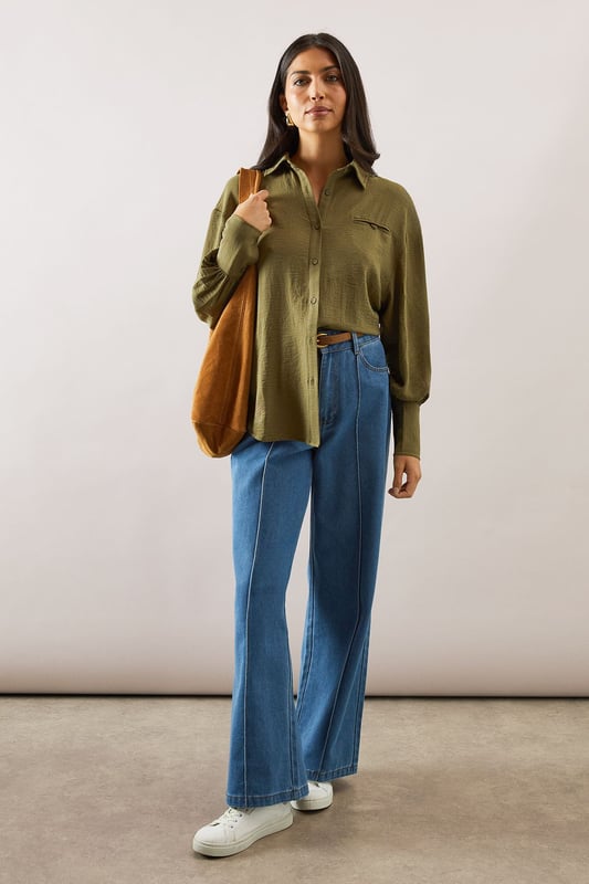 Relaxed fit collared shirt with elegant chest pocket detail
        Voluminous balloon sleeves with fitted cuffs for a feminine silhouette
        Soft woven fabric with slight stretch for all-day comfort
        Classic button-through front with sophisticated collar design
        Curved hem perfect for both tucked or untucked styling options
    
    This versatile Wallis shirt combines sophistication with everyday comfort. The relaxed silhouette drapes beautifully over the body while the distinctive pocket detail adds a touch of refinement. Style it as shown with wide-leg denim trousers and trainers for a polished daytime look, or tuck the front into tailored trousers for family gatherings. The balloon sleeves create a contemporary shape that transitions effortlessly from office to weekend brunch. For cooler days, layer under a lightweight cardigan or pair with your favourite jeans and ankle boots. The collared neckline frames the face beautifully, making this shirt an essential addition to your daywear collection - perfect for those occasions when you want to feel put-together yet comfortable.