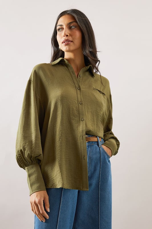 Relaxed fit collared shirt with elegant chest pocket detail
        Voluminous balloon sleeves with fitted cuffs for a feminine silhouette
        Soft woven fabric with slight stretch for all-day comfort
        Classic button-through front with sophisticated collar design
        Curved hem perfect for both tucked or untucked styling options
    
    This versatile Wallis shirt combines sophistication with everyday comfort. The relaxed silhouette drapes beautifully over the body while the distinctive pocket detail adds a touch of refinement. Style it as shown with wide-leg denim trousers and trainers for a polished daytime look, or tuck the front into tailored trousers for family gatherings. The balloon sleeves create a contemporary shape that transitions effortlessly from office to weekend brunch. For cooler days, layer under a lightweight cardigan or pair with your favourite jeans and ankle boots. The collared neckline frames the face beautifully, making this shirt an essential addition to your daywear collection - perfect for those occasions when you want to feel put-together yet comfortable.