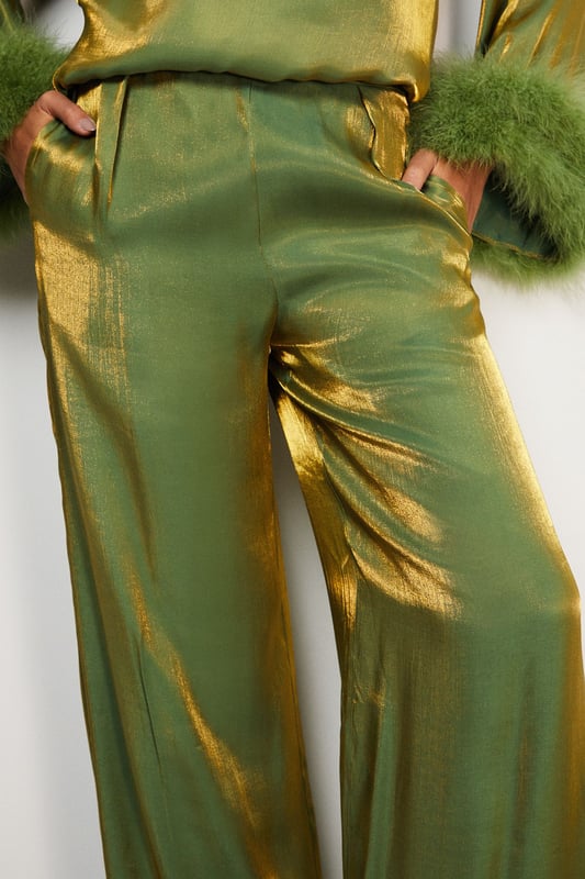 Luxurious feather trim adorning cuffs and hem
        Wide-leg silhouette for a dramatic, flowing effect
        High-waisted design for a flattering fit
        Iridescent fabric adding a subtle shimmer
        Ankle-length cut perfect for showcasing statement footwear
    
    Make a grand entrance at your next formal event with these show-stopping wide-leg trousers from Warehouse. The iridescent fabric catches the light beautifully, whilst the opulent feather trim at the cuffs and hem adds a touch of old Hollywood glamour. Style these trousers with a sleek, fitted top to balance the voluminous silhouette. For an ultra-chic ensemble, pair with metallic platform sandals and a clutch bag. These trousers are versatile enough for a range of occasions, from black-tie galas to winter weddings. The high-waisted cut elongates the legs, creating a statuesque silhouette that's sure to turn heads. Embrace your inner fashionista and let these trousers be the star of your outfit.