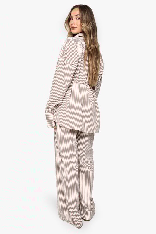 Wide leg maternity trousers with flattering silhouette for growing bumps
        Coordinating belt detail to adjust fit throughout pregnancy
        Vertical stripe pattern creates an elongating effect
        Comfortable high-rise waistband sits above the bump
        Designed to be paired with matching striped shirt for a coordinated look
    
    These boohoo maternity trousers combine comfort and style with their relaxed wide-leg design. The adjustable belt allows you to customise the fit as your body changes, while the vertical stripes create a lengthening effect for a flattering silhouette. Style with the matching button-up shirt for an on-trend coordinated set that works brilliantly for casual outings. For daytime gatherings, pair with simple trainers and oversized sunglasses, or dress up with ballet flats and delicate jewellery for family occasions. The versatile design transitions seamlessly between seasons-layer with a lightweight cardigan when temperatures drop or wear alone during warmer months. These trousers offer the perfect balance of comfort and contemporary style for the fashion-forward mum-to-be.