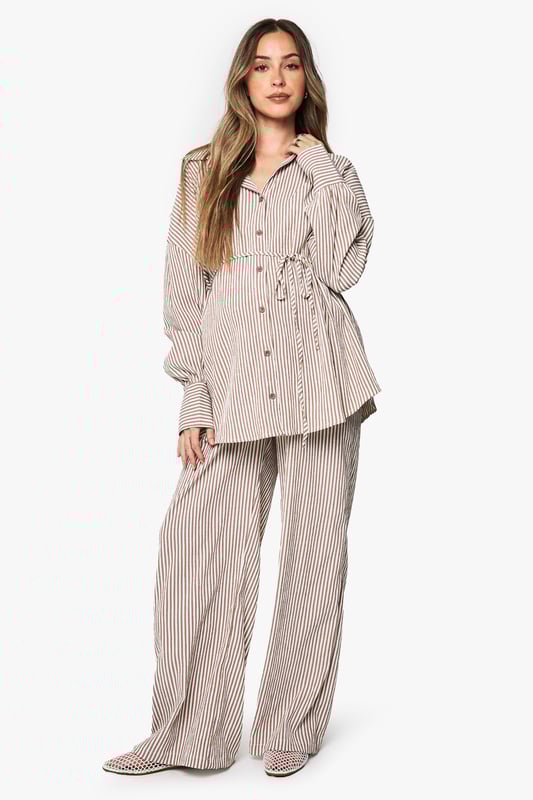 Wide leg maternity trousers with flattering silhouette for growing bumps
        Coordinating belt detail to adjust fit throughout pregnancy
        Vertical stripe pattern creates an elongating effect
        Comfortable high-rise waistband sits above the bump
        Designed to be paired with matching striped shirt for a coordinated look
    
    These boohoo maternity trousers combine comfort and style with their relaxed wide-leg design. The adjustable belt allows you to customise the fit as your body changes, while the vertical stripes create a lengthening effect for a flattering silhouette. Style with the matching button-up shirt for an on-trend coordinated set that works brilliantly for casual outings. For daytime gatherings, pair with simple trainers and oversized sunglasses, or dress up with ballet flats and delicate jewellery for family occasions. The versatile design transitions seamlessly between seasons-layer with a lightweight cardigan when temperatures drop or wear alone during warmer months. These trousers offer the perfect balance of comfort and contemporary style for the fashion-forward mum-to-be.